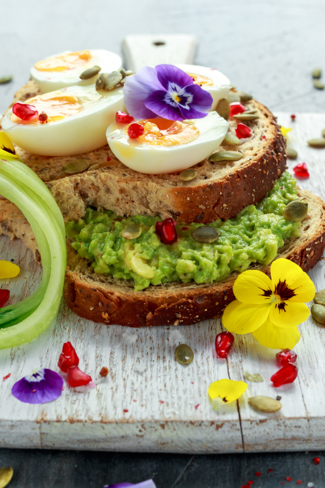 Сендвич с яйцом и цветами на доске