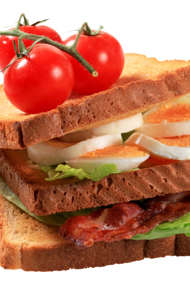 Сэндвич с яйцами, беконом и помидорами на белом фоне