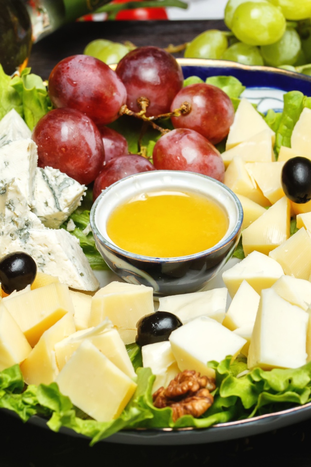 Нарезанный сыр на тарелке в виноградом 