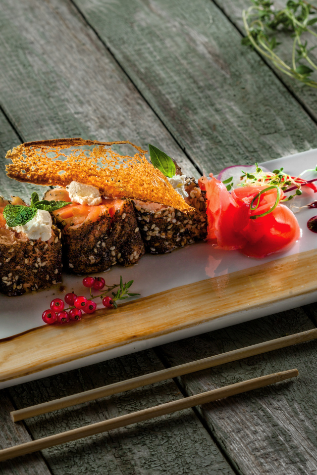 Суши на тарелке на деревянном столе с соусом