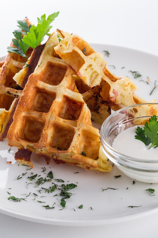 Несладкие вафли на белой тарелке с зеленью и соусом