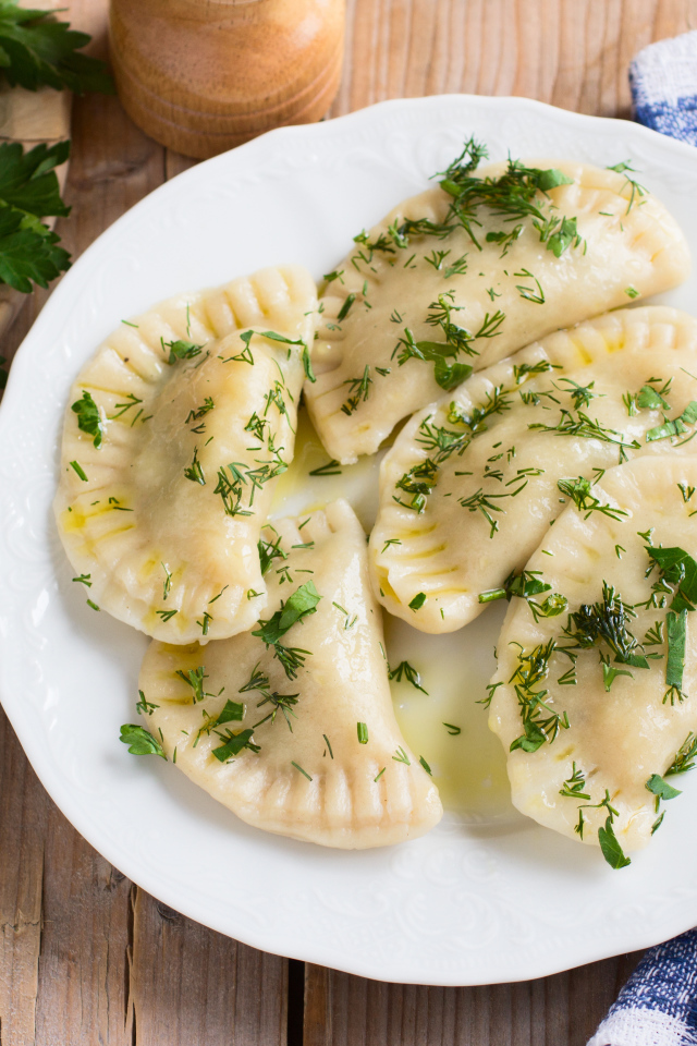 Вареники с зеленью на белой тарелке 