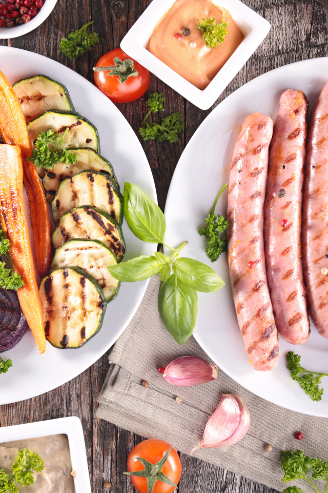 Овощи и сосиски гриль на столе с соусом