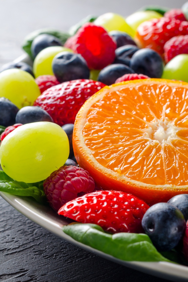 Аппетитные ягоды на тарелке с зелеными листьями базилика