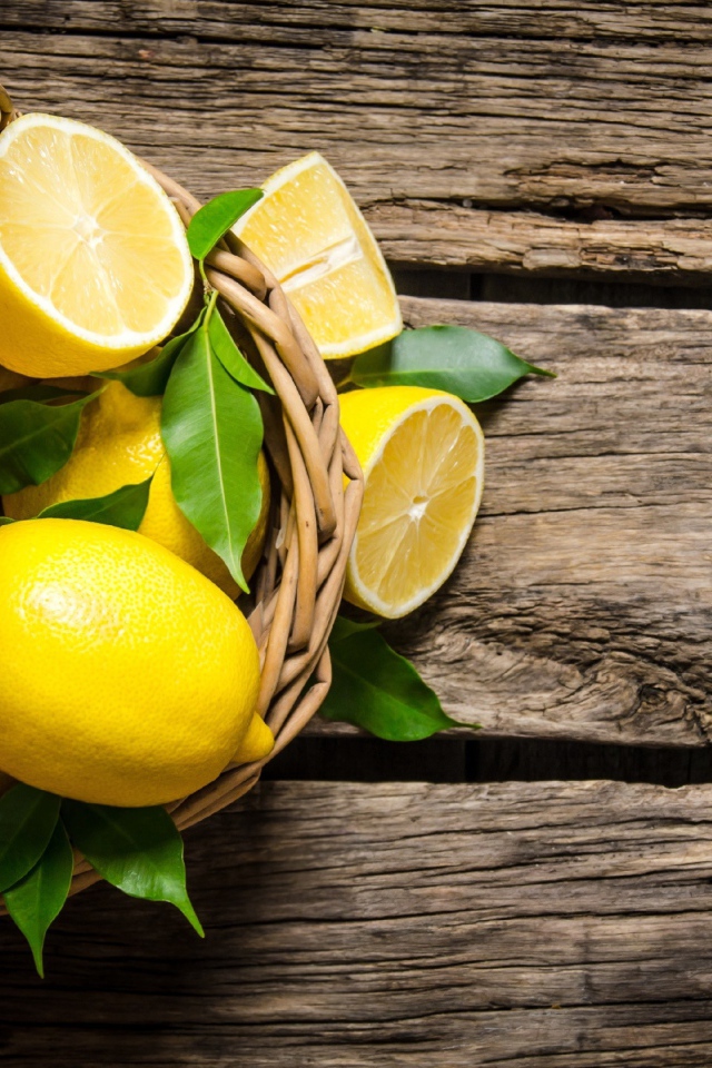 Красивые желтые лимоны в корзине на деревянном столе