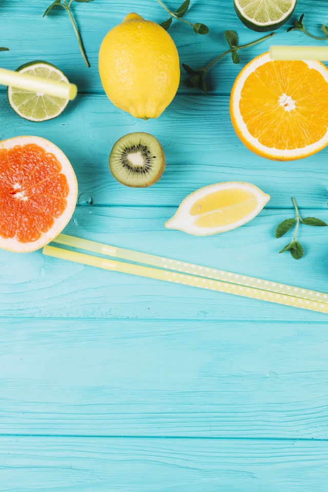 Цитрусовые фрукты на голубом столе с мятой и лимонадом