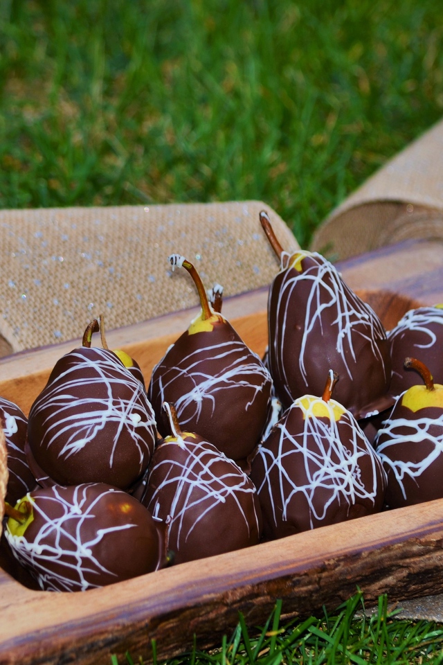 Груши в шоколадной глазури стоят на зеленой траве