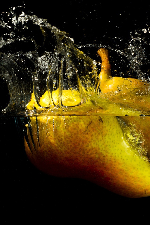 Груши в воде с брызгами на черном фоне
