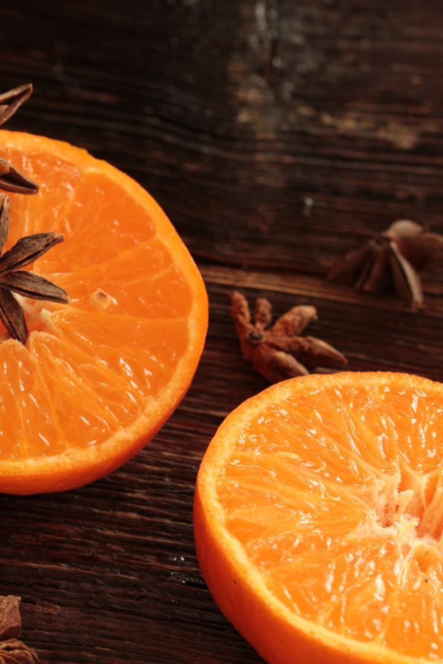 Две половины апельсина на деревянном столе с бадьяном