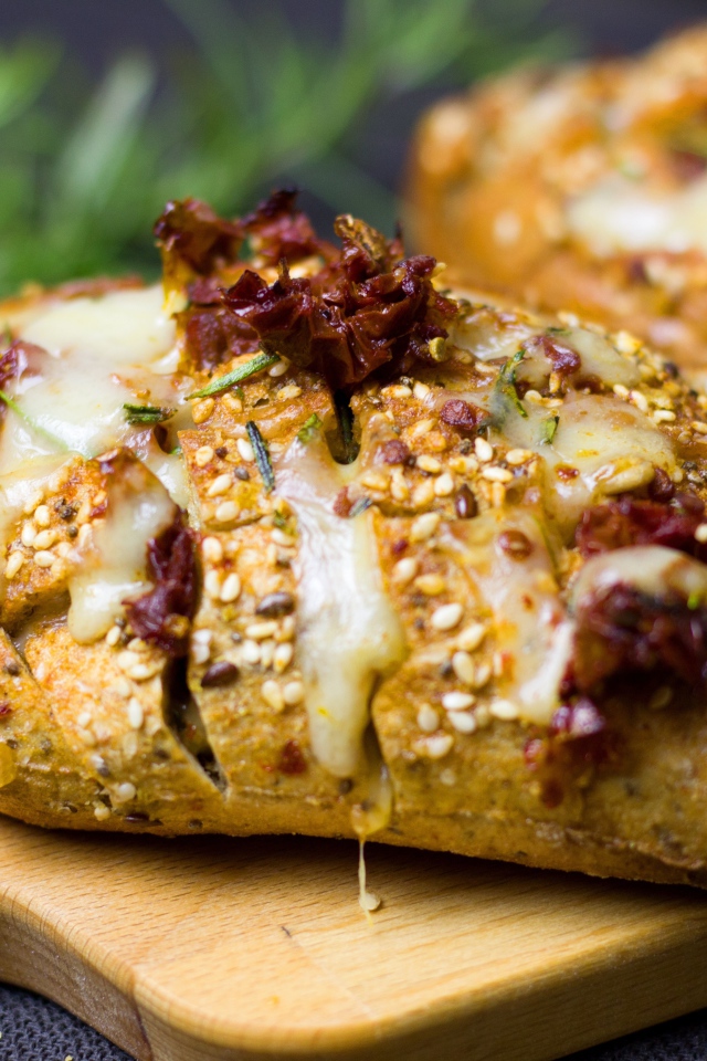 Булочка с кунжутом и сыром на разделочной доске 