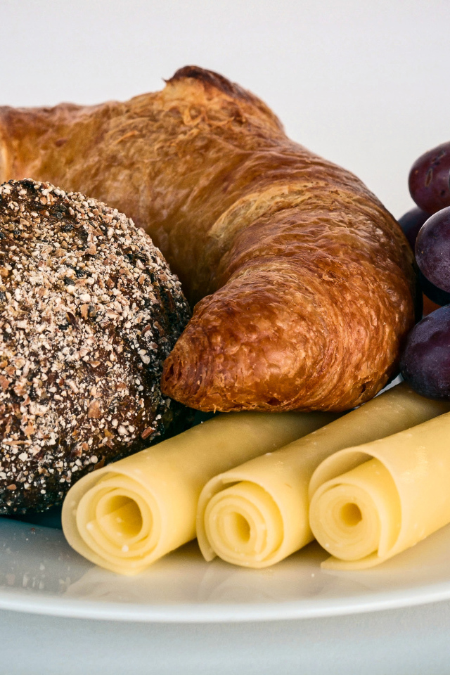 Свежая выпечка с сыром и розовым виноградом на белой тарелке 