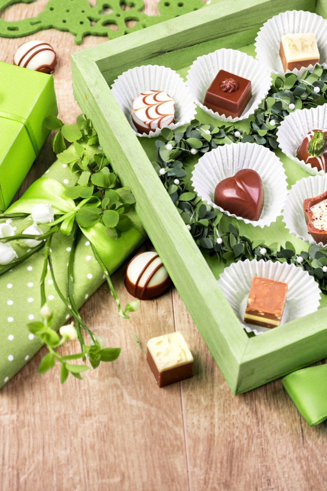 Коробка шоколадных конфет с подарком на столе