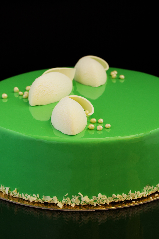 Зеленый глянцевый торт отражается в черной поверхности 