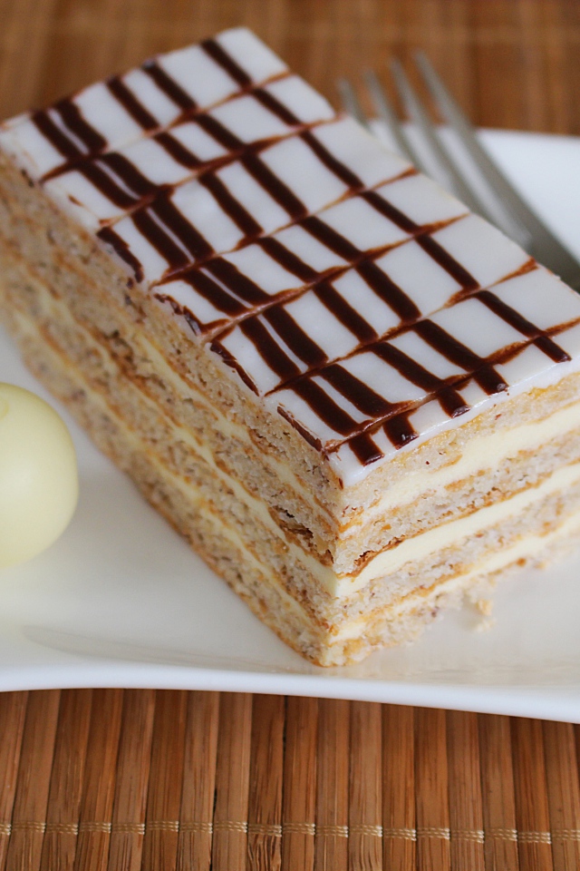 Кусок торта на белой тарелке с вилкой и конфетой 