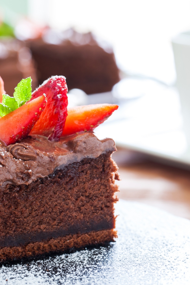 Кусок пирога с шоколадным кремом и кусочками спелой клубники 