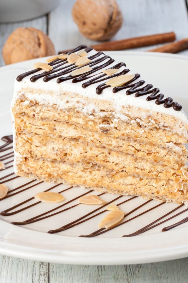 Кусок торта с орехами и шоколадом на белой тарелке