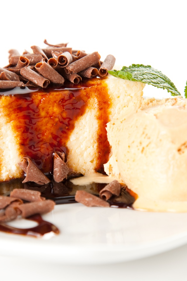 Кусок чизкейка с шоколадом и шариком мороженого на белой тарелке 