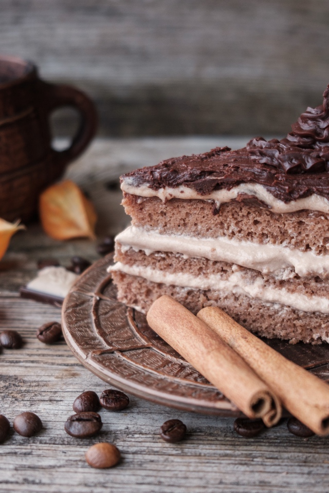 Кусок торта с корицей на столе с шоколадом и чашкой кофе