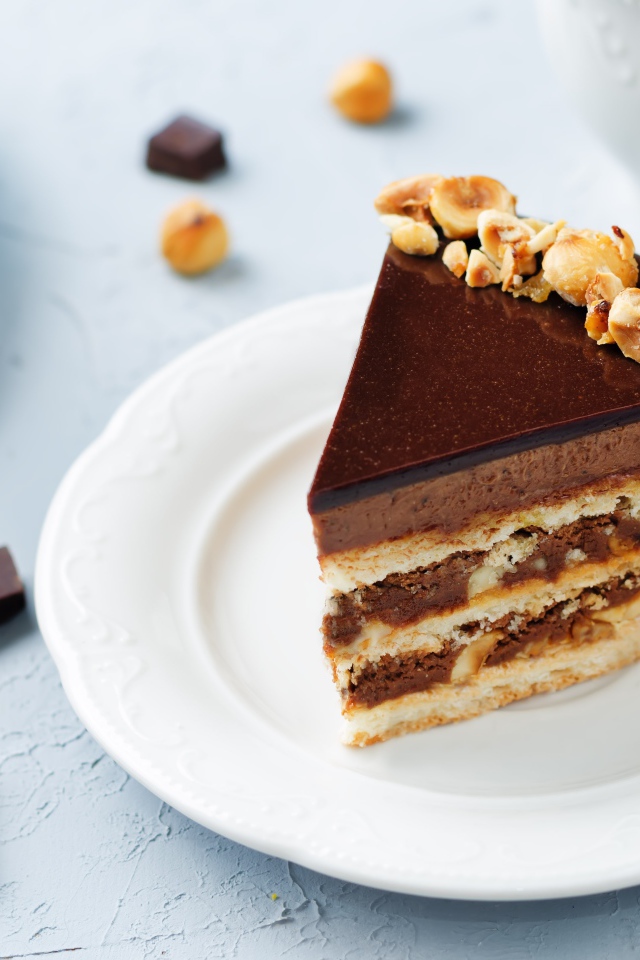 Кусок аппетитного торта с орехами на белой тарелке