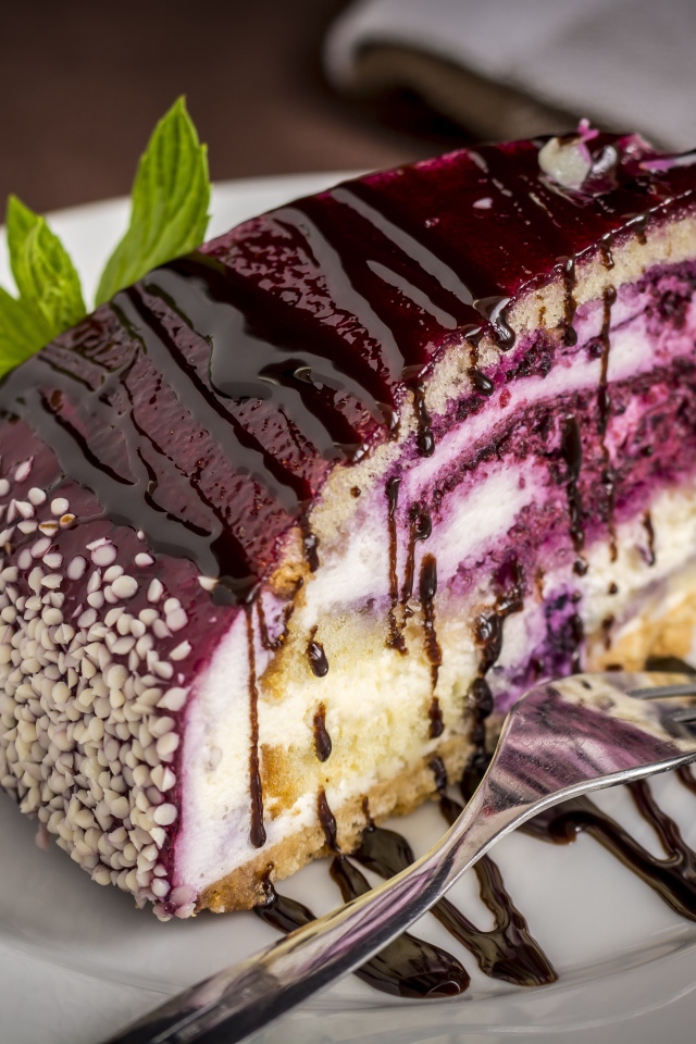 Кусок черничного пирога с джемом на белой тарелке с вилкой