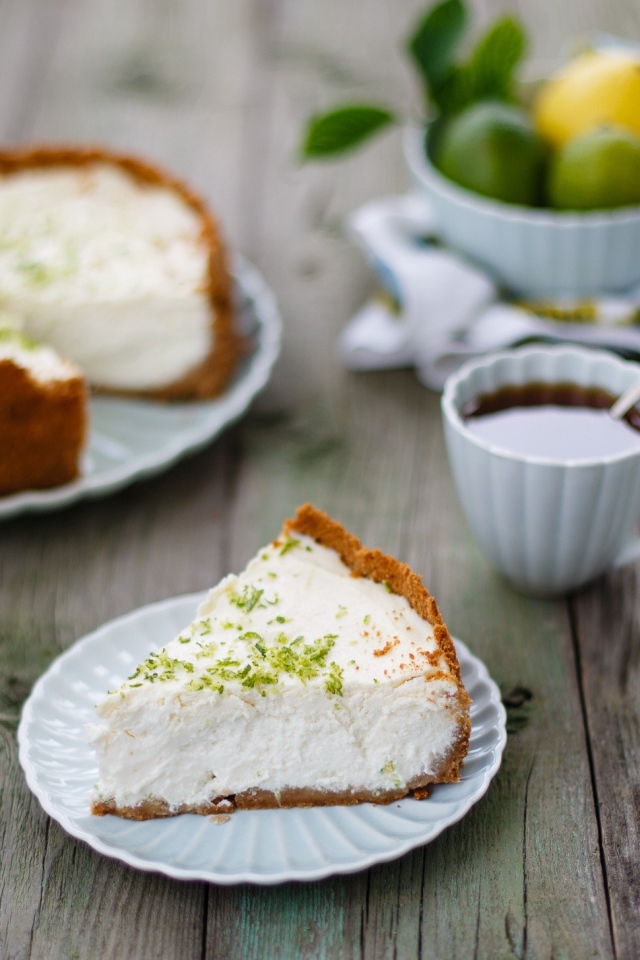 Кусок чизкейка на столе с чашкой чая