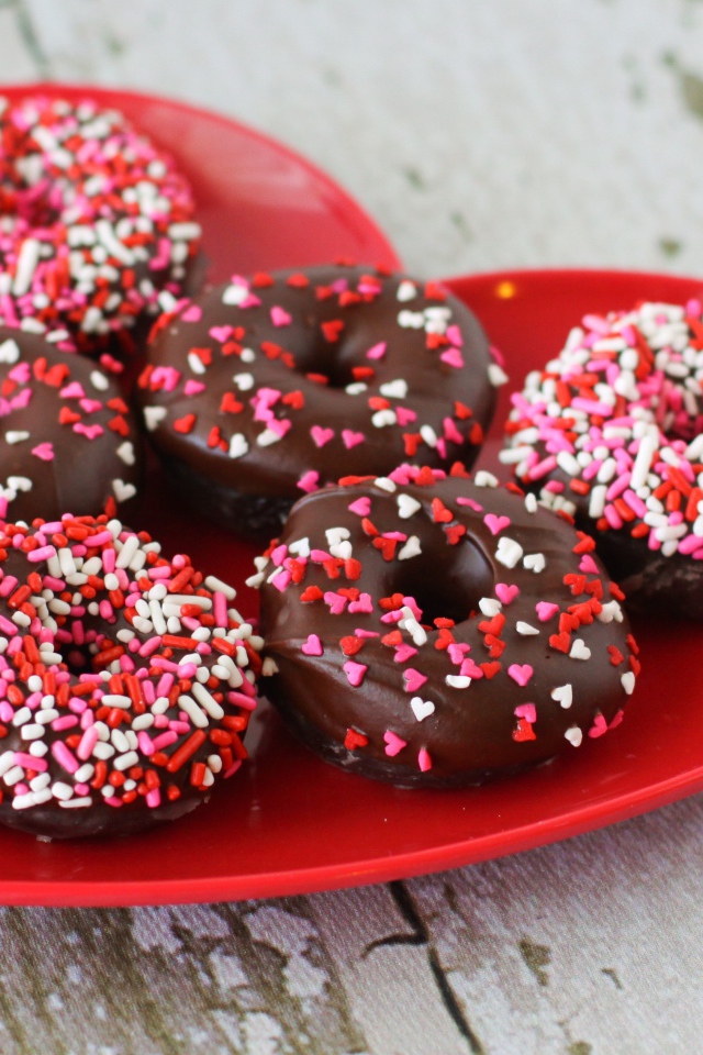 Аппетитные пончики на красной тарелке в форме сердца