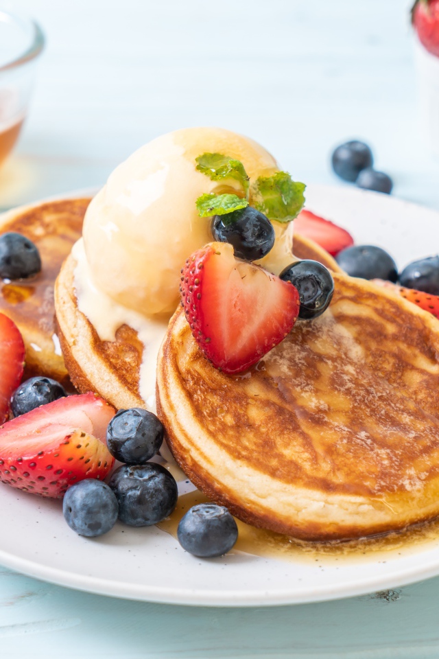 Аппетитные оладьи с мороженым, медом и ягодами клубники и черники