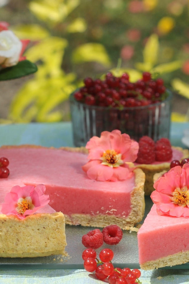 Аппетитный пирог с ягодами малины и красной смородины на столе с цветами