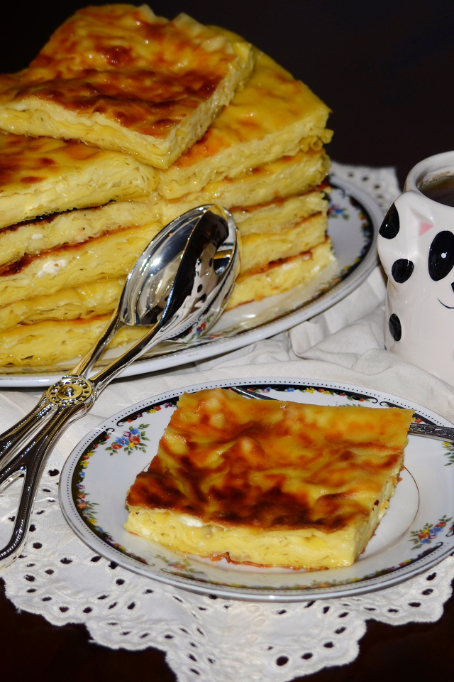 Аппетитный сладкий пирог с чашкой чая на столе