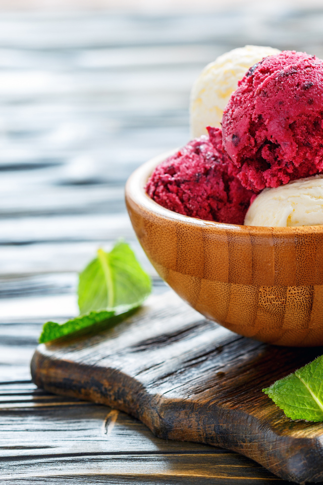 Шарики фруктового и ванильного мороженого в деревянной миске на столе