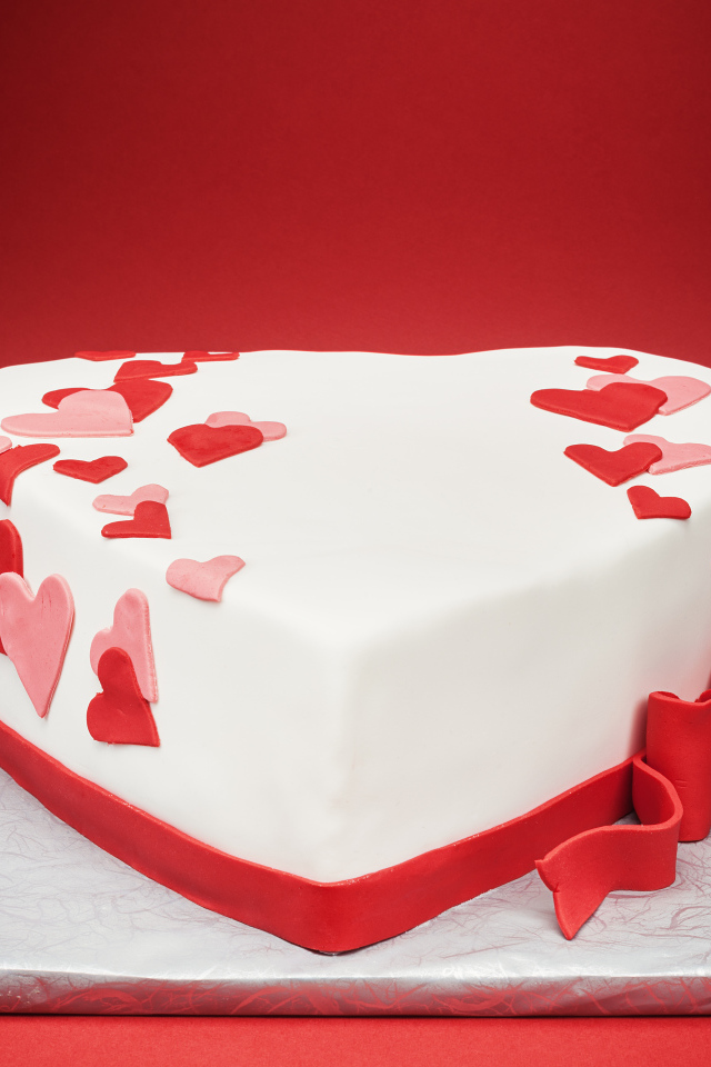 Красивый торт в форме сердца на красном фоне