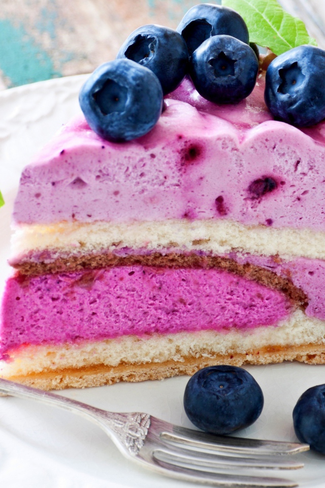 Торт с черничным муссом и свежими ягодами черники на белой тарелке 