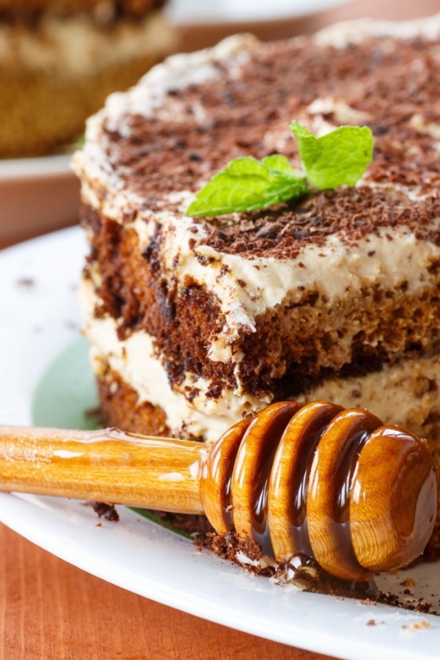 Торт с кремом и шоколадом на тарелке с ложкой для меда