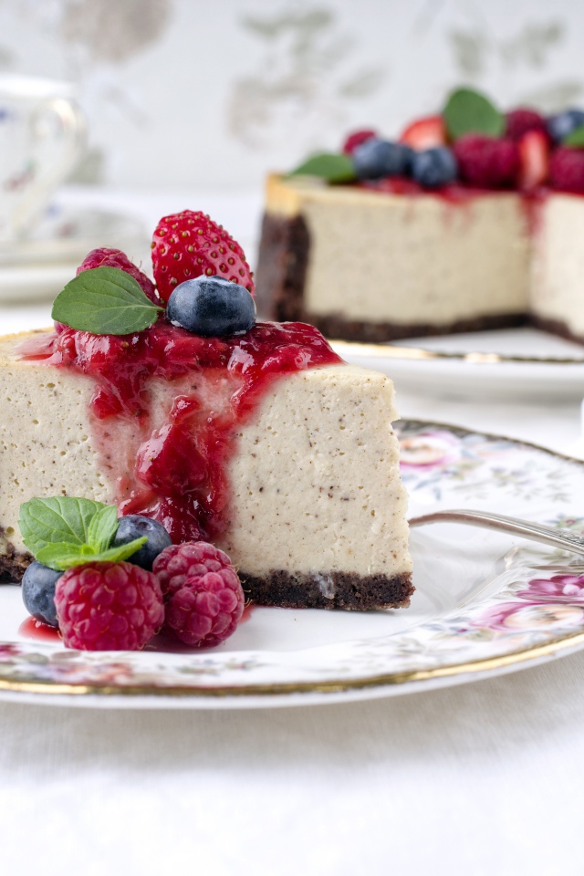 Чизкейк на столе с ягодами малины, черники и клубники