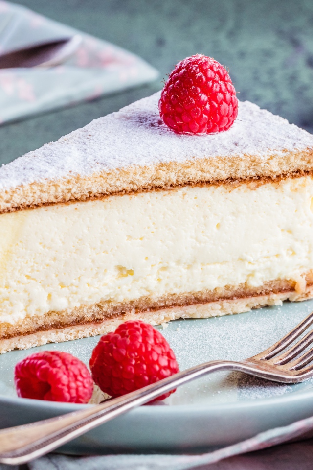 Чизкейк с сахарной пудрой и ягодами малины на тарелке