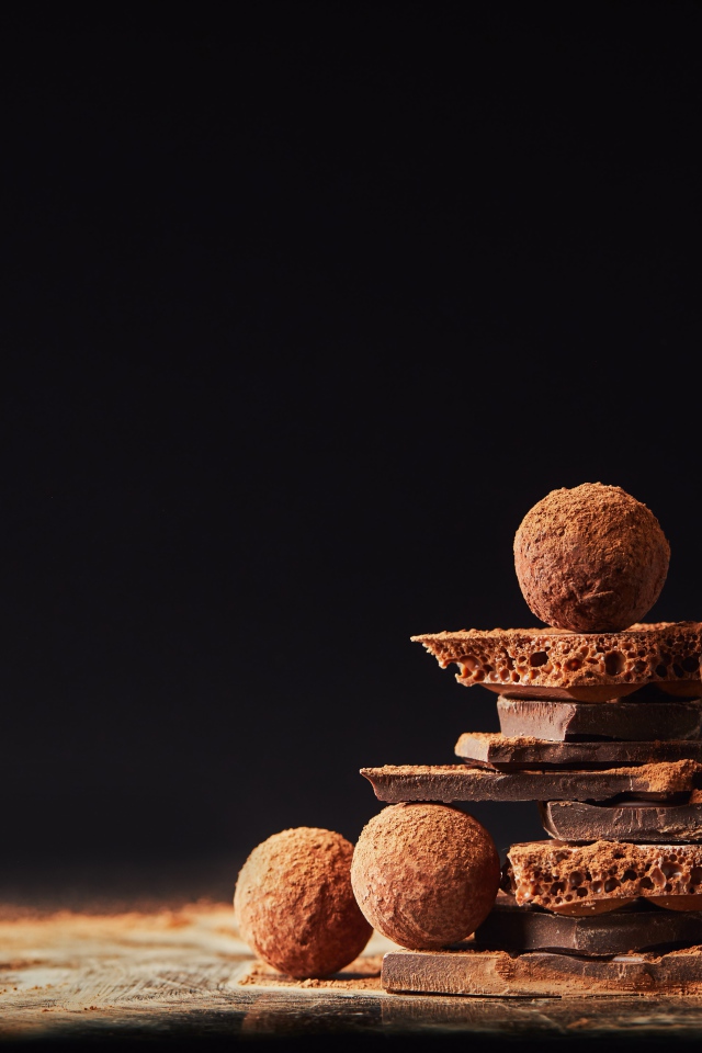 Шоколадные шарики и кусочки шоколада на черном фоне