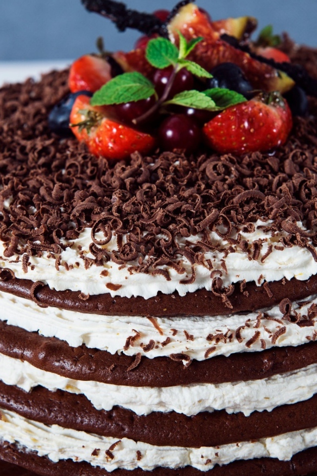 Шоколадный торт с кремом и тертым шоколадом украшен ягодами