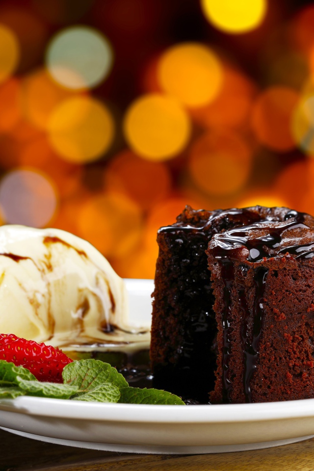 Шоколадное пирожное с мороженым и клубникой на тарелке