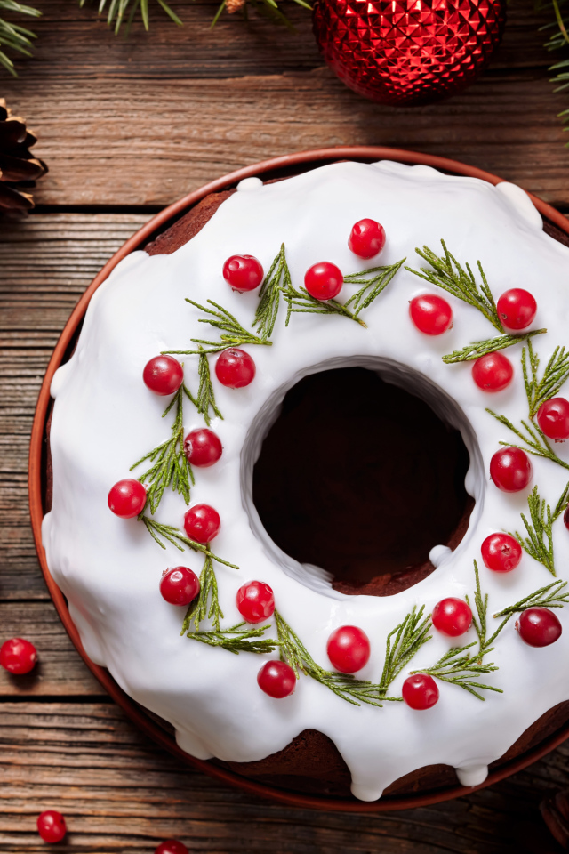 Рождественский пирог с ягодами клюквы на деревянном столе с еловыми ветками