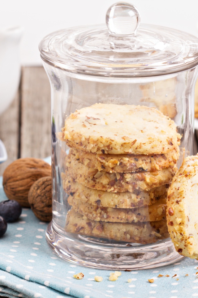 Печенье в стеклянной банке на столе с орехами и черникой