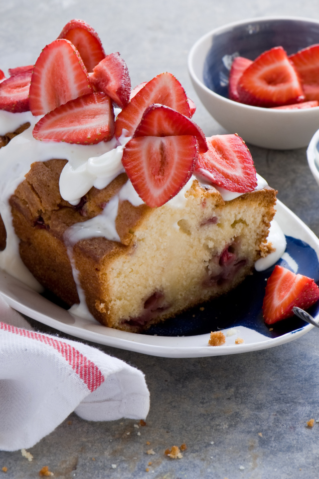 Кекс с кремом на тарелке со свежей клубникой 