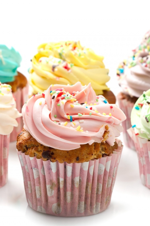 Кексы с разноцветным кремом на белом фоне