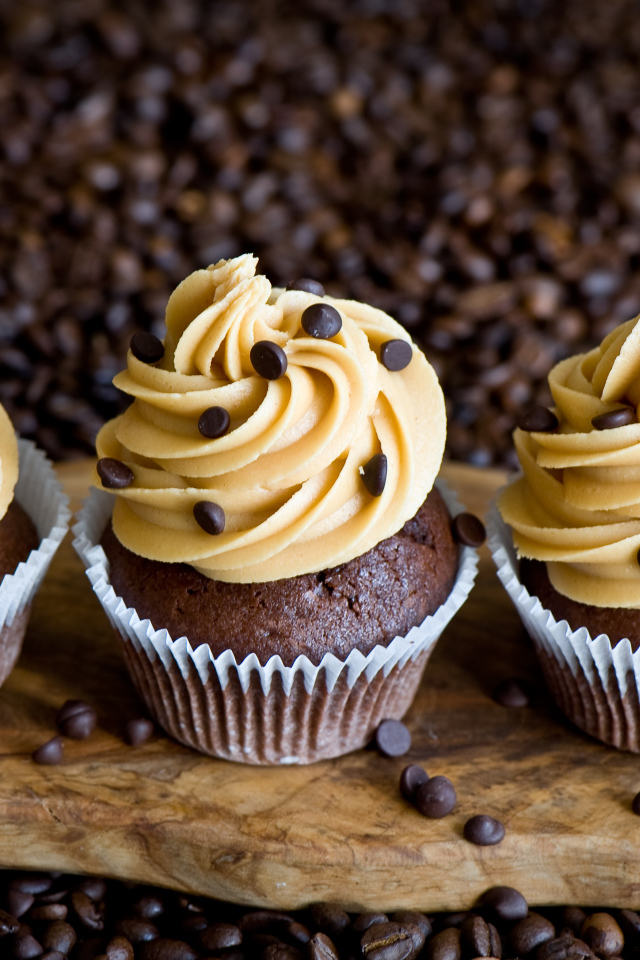 Кексы с кремом и зернами кофе на столе 