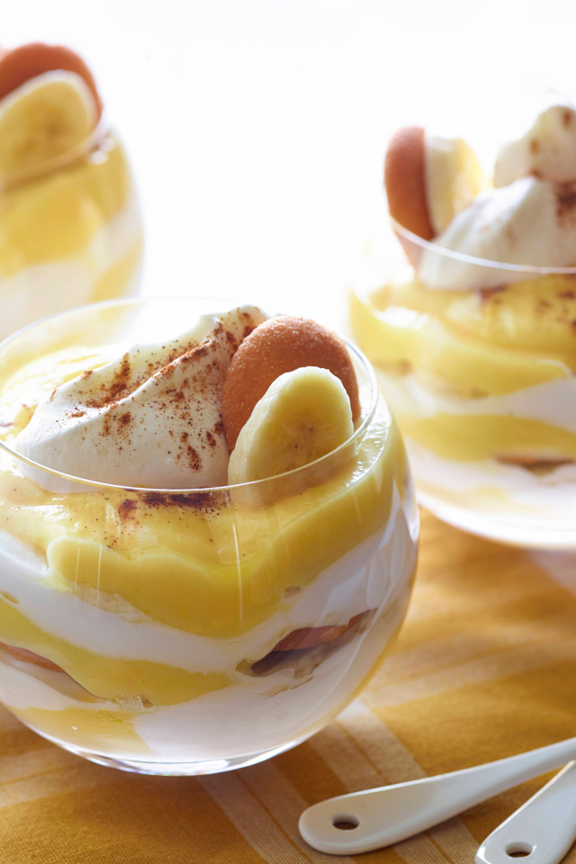 Десерт с бананами и печеньем в стаканах на столе 