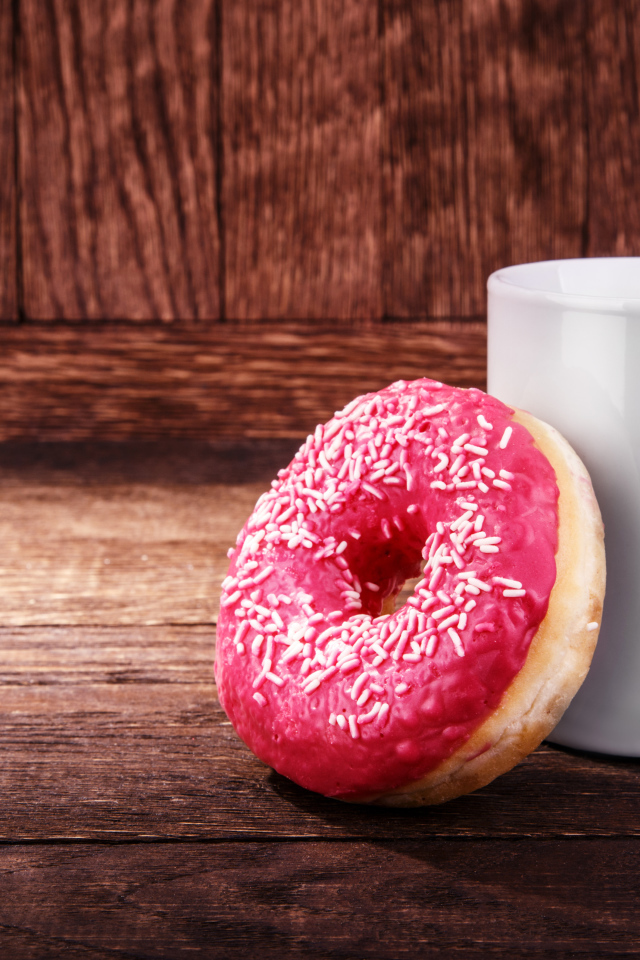 Пончик с белой кружкой на деревянном столе