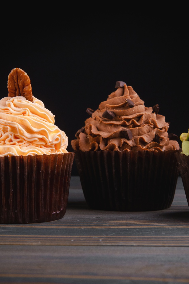 Четыре аппетитных капкейка с кремом на черном фоне