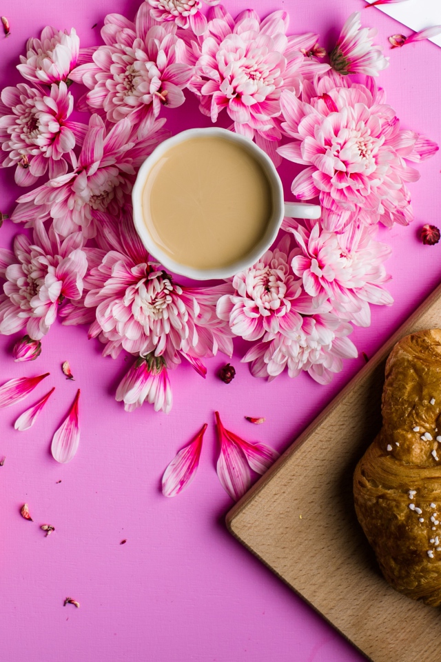 Свежие круассаны на столе с чашкой какао и цветами хризантемы