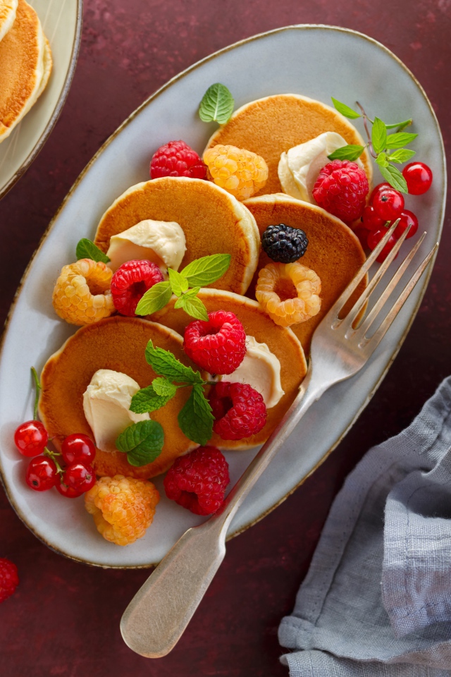 Оладьи на столе с ягодами малины и мороженым