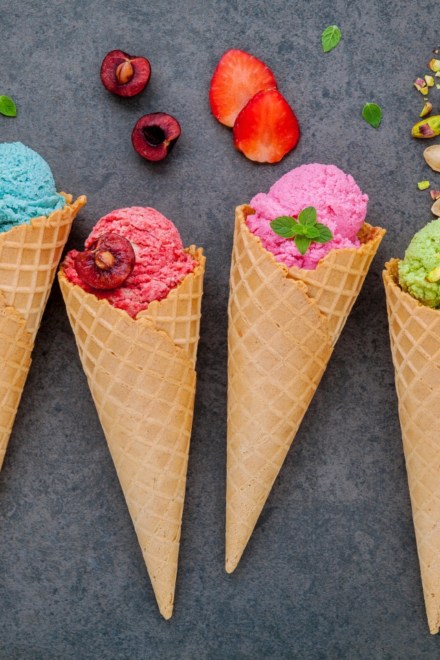 Шарики фруктового мороженого в вафельных рожках на сером фоне