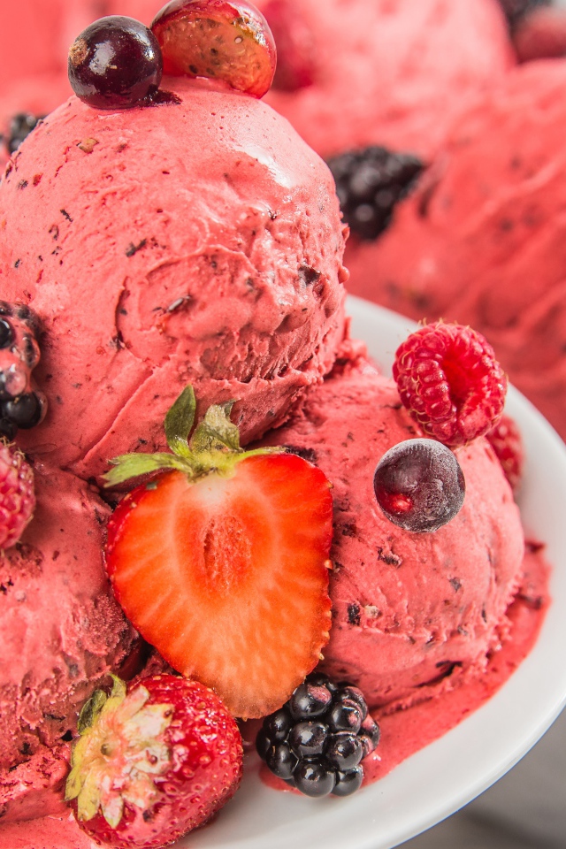 Шарики фруктового мороженого на тарелке с ягодами 